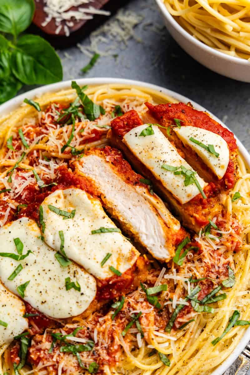 Closeup of Chicken Parmesan Sliced on a Plate or Pasta.