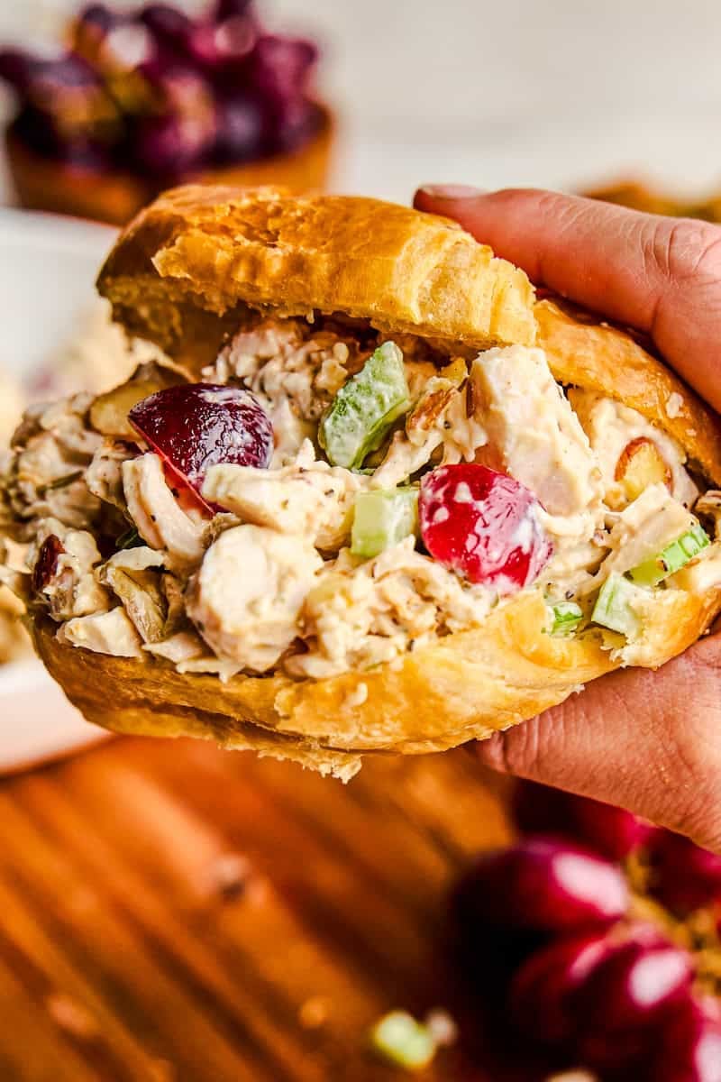 Hand holding a traditional chicken salad in a croissant.