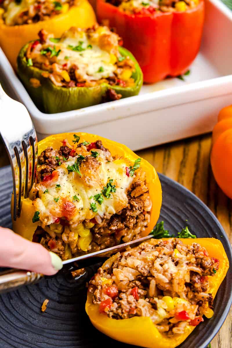 A cheese topped stuffed yellow bell pepper sliced in half revealing the filling.