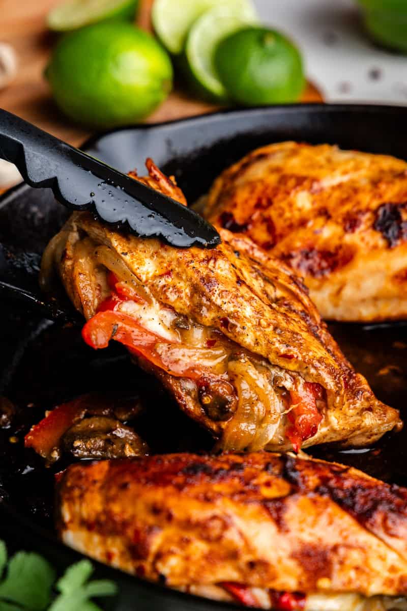 Closeup of Fajita Stuffed chicken on a skillet being lifted by Tongs.