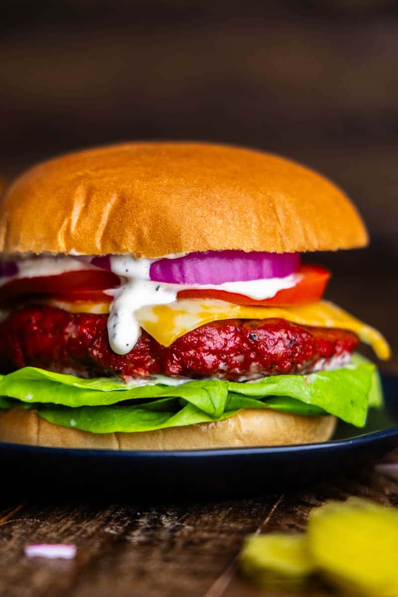A close up view of a smoked burger on a black plate.