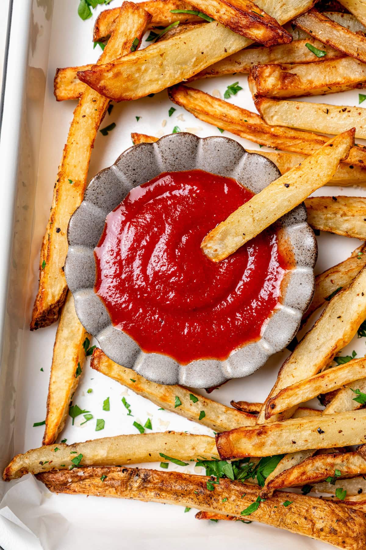 A healthy recipe for homemade ketchup with no high fructose corn syrup. Instead it's sweetened naturally with honey and it tastes amazing! French fry dipping into small bowl of ketchup
