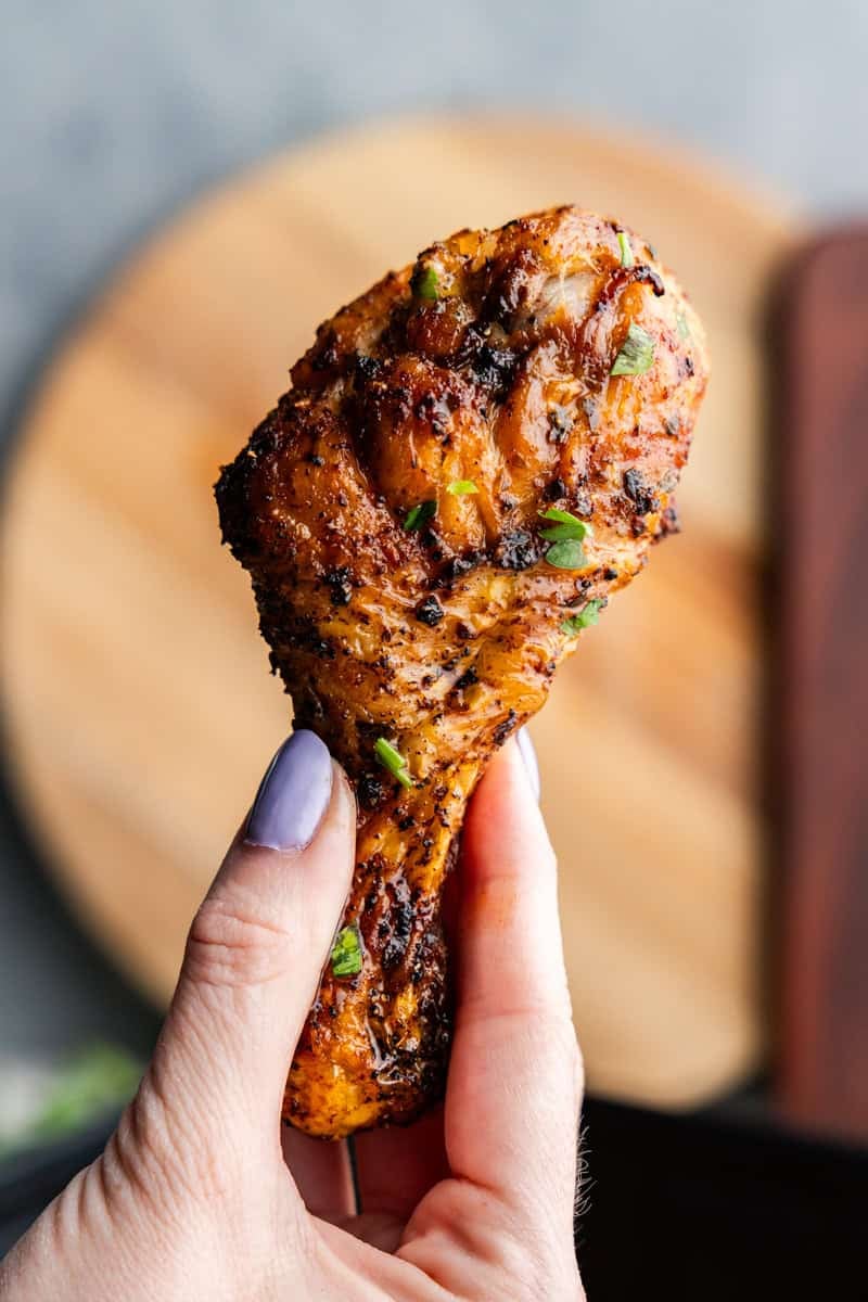 Closeup of a chicken drumstick being hero over the air fryer.