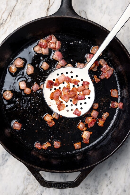 Bacon being removed from skillet.