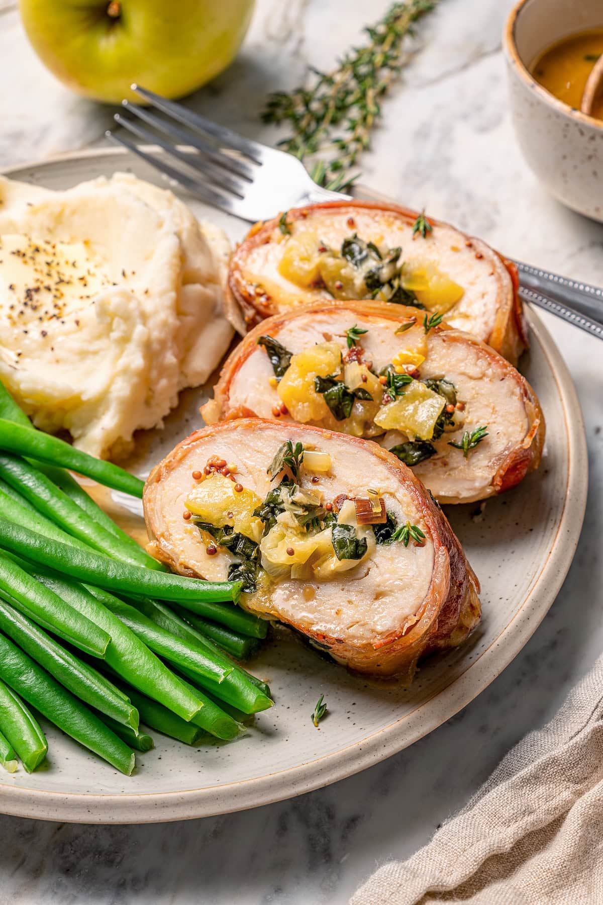 Three slices of prosciutto-wrapped stuffed turkey tenderloin with kale and apple.