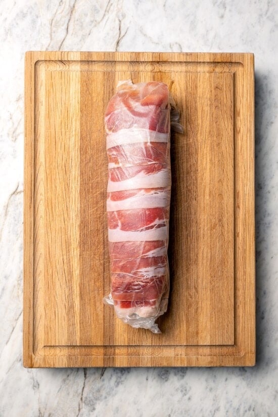 Turkey tenderloin wrapped in prosciutto and layer of plastic wrap.