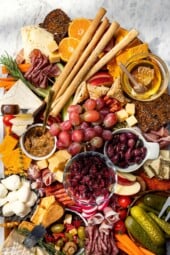 Charcuterie and cheese board with fruit, olives, and spreads.