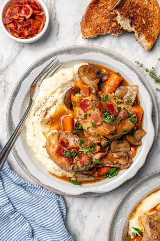 Bowl of mashed potatoes topped with slow cooker coq au vin.