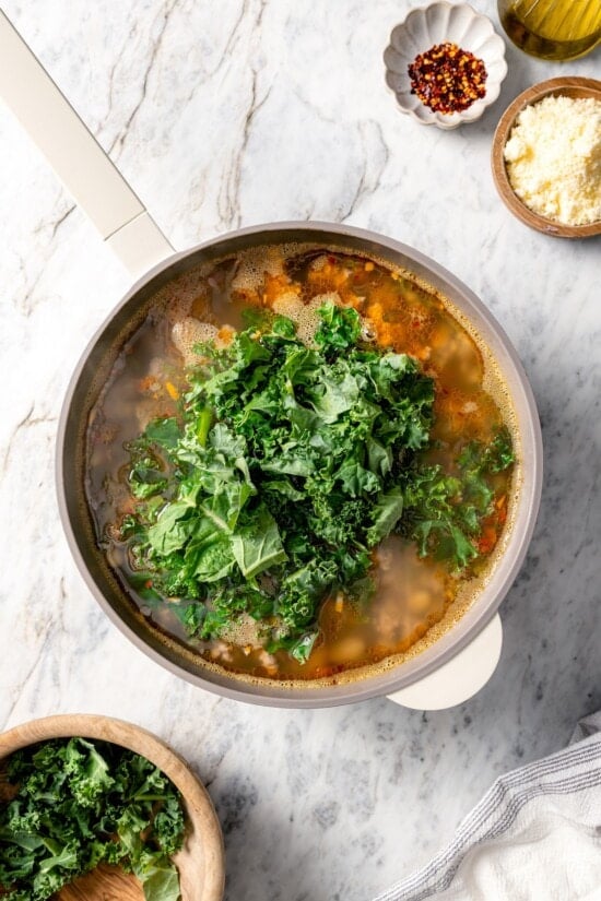 Kale added to pot of white bean soup.