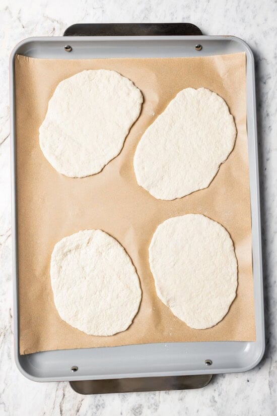 Dough for breakfast pizzas on parchment-lined pan.