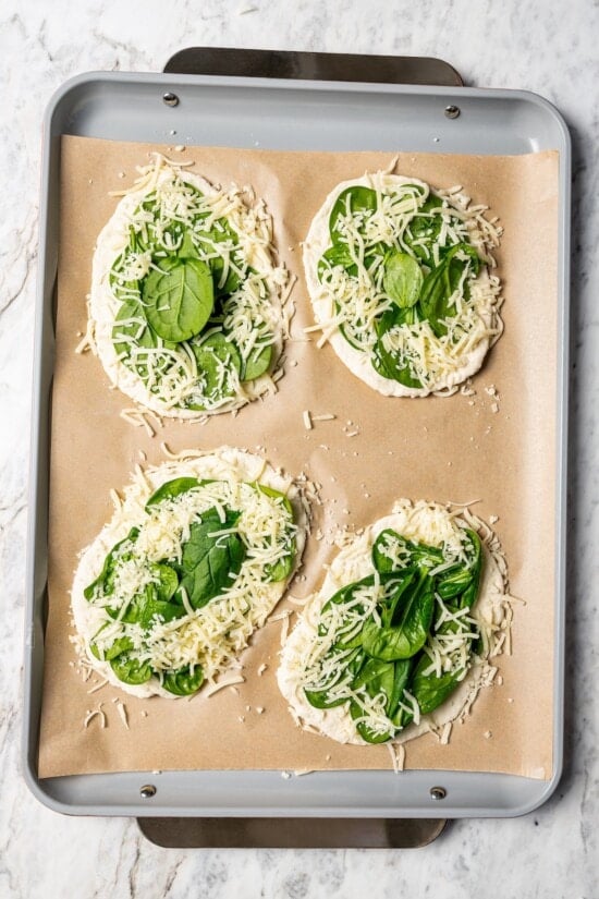 Breakfast pizzas topped with mozzarella and spinach.