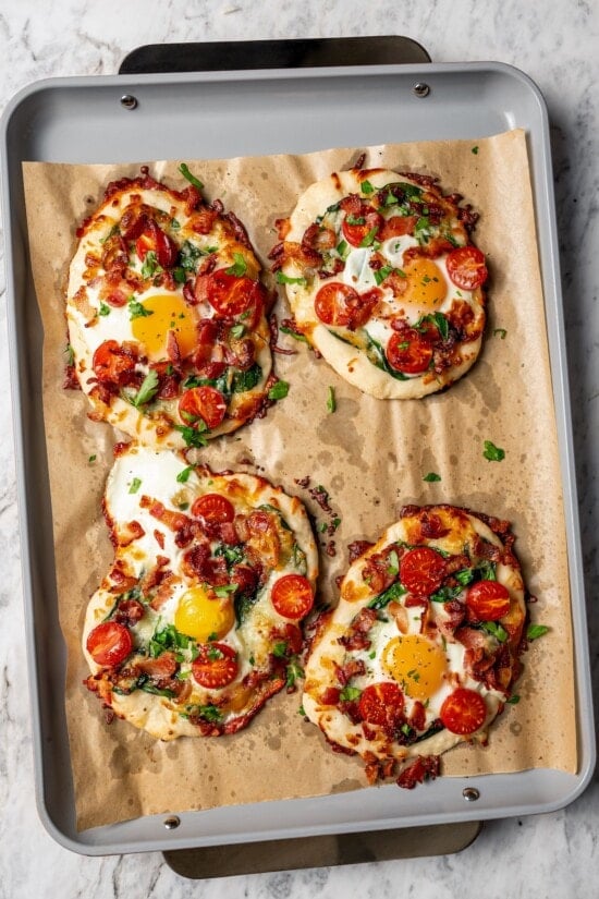 4 persona breakfast pizzas on parchment-lined pan.