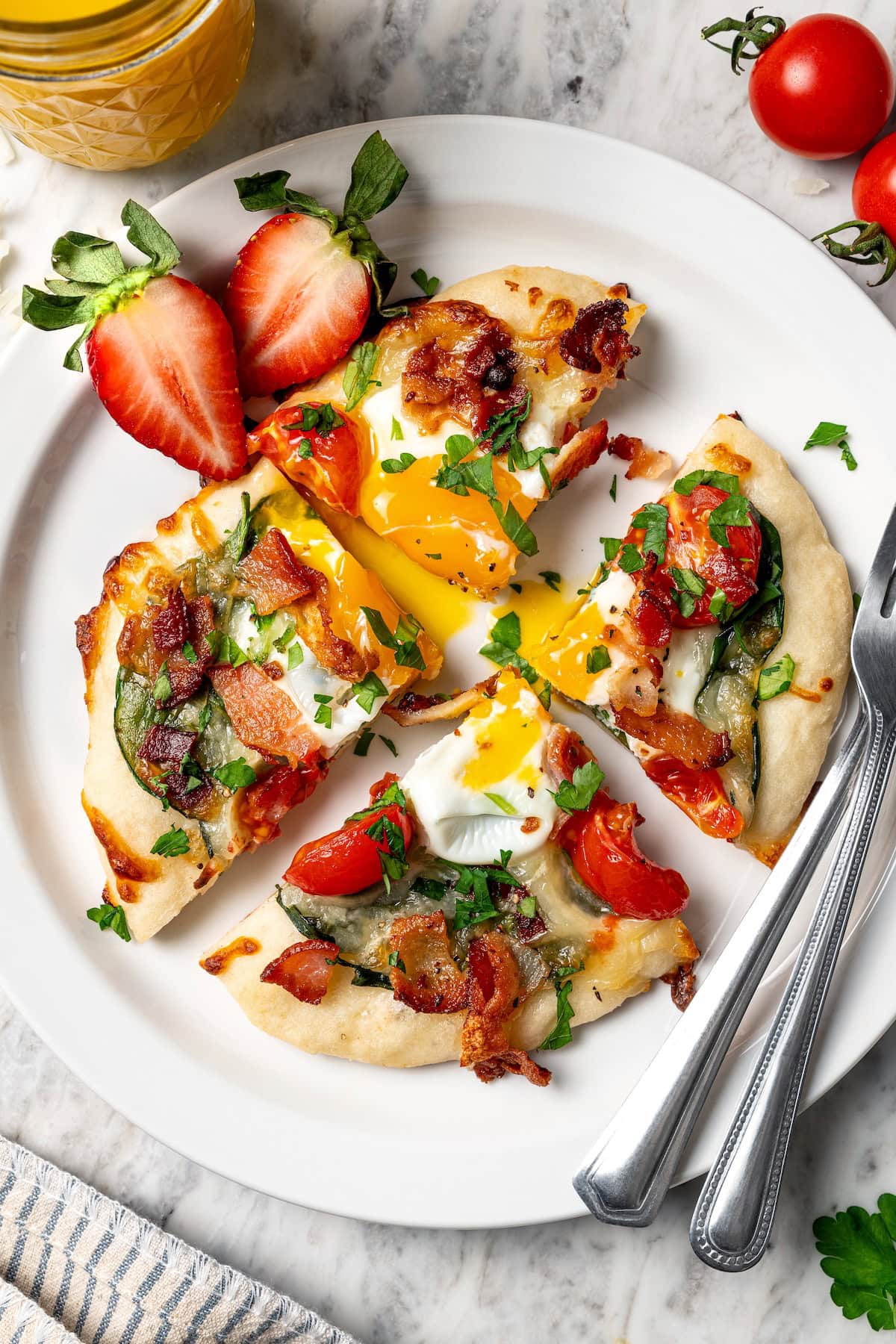 Breakfast pizza on plate with runny yolk, sliced into quarters.