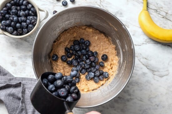 Adding blueberries to banana bread batter.