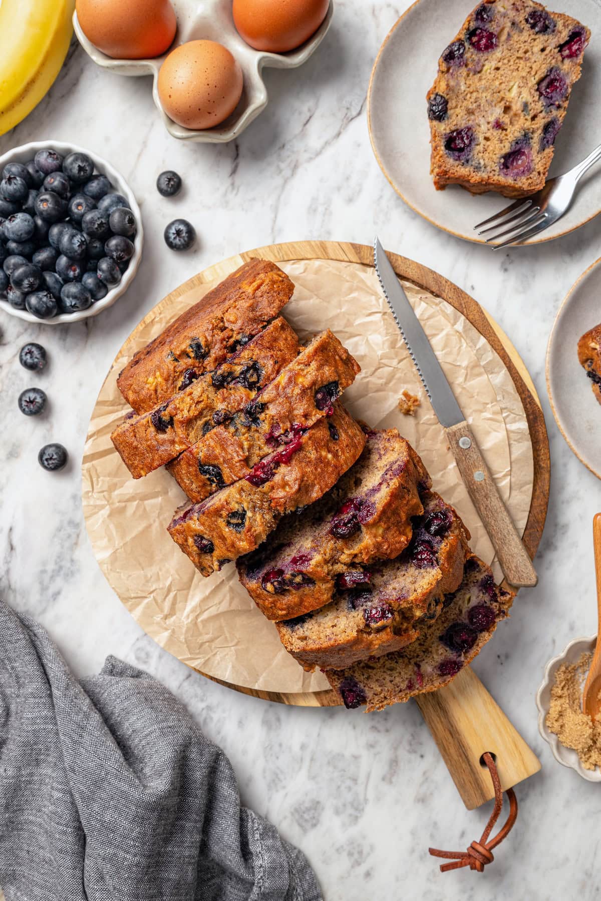 Sliced loaf of blueberry banana bread on cutting board.