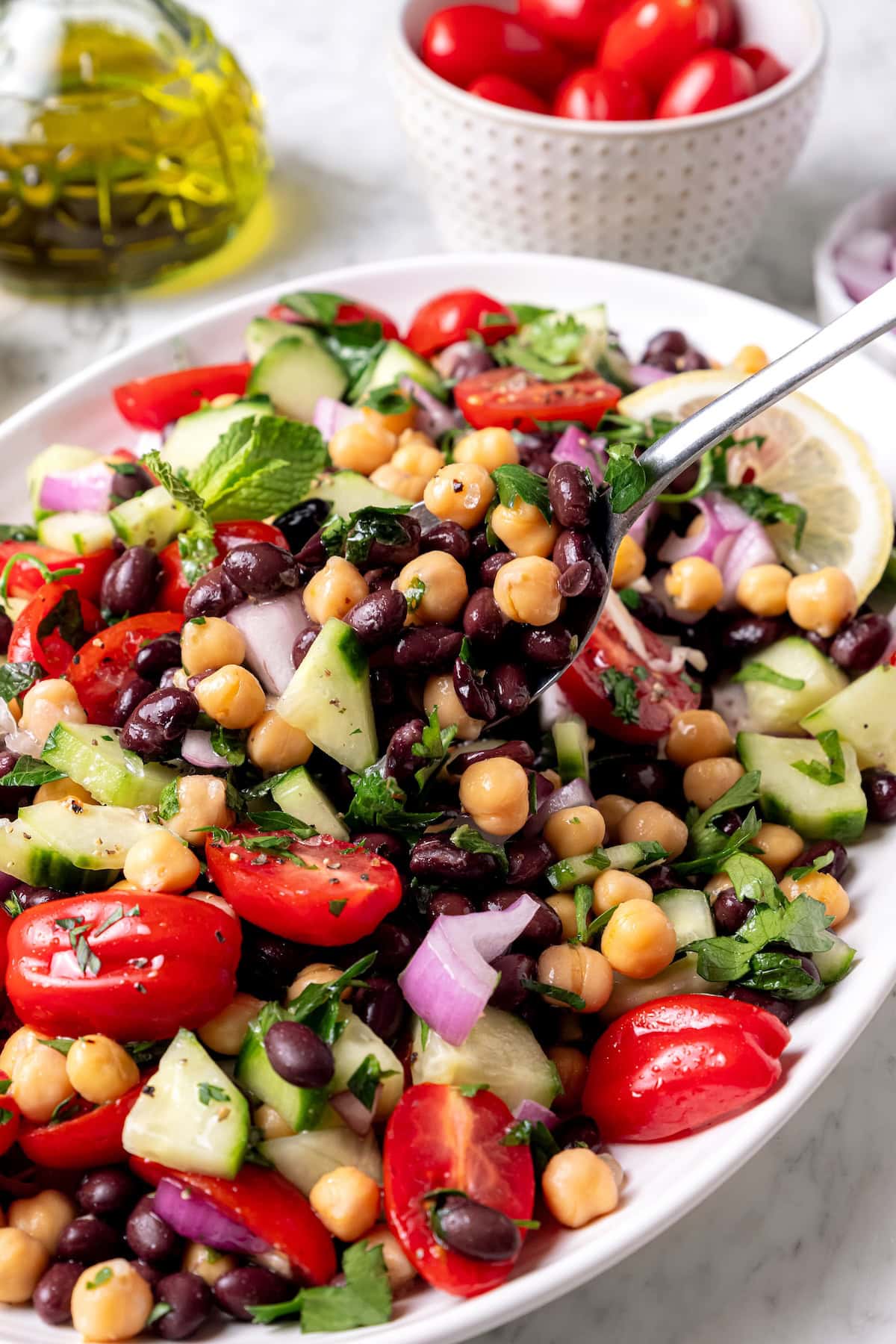 Garbanzo bean Mediterranean salad in serving spoon held over bowl.