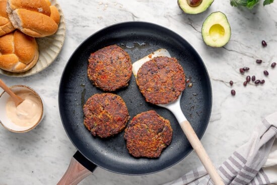 Spatula lifting black bean burger from pan.