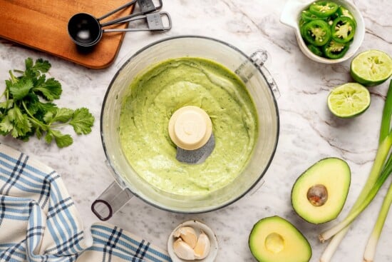 Zesty avocado cilantro lime dressing in food processor bowl.