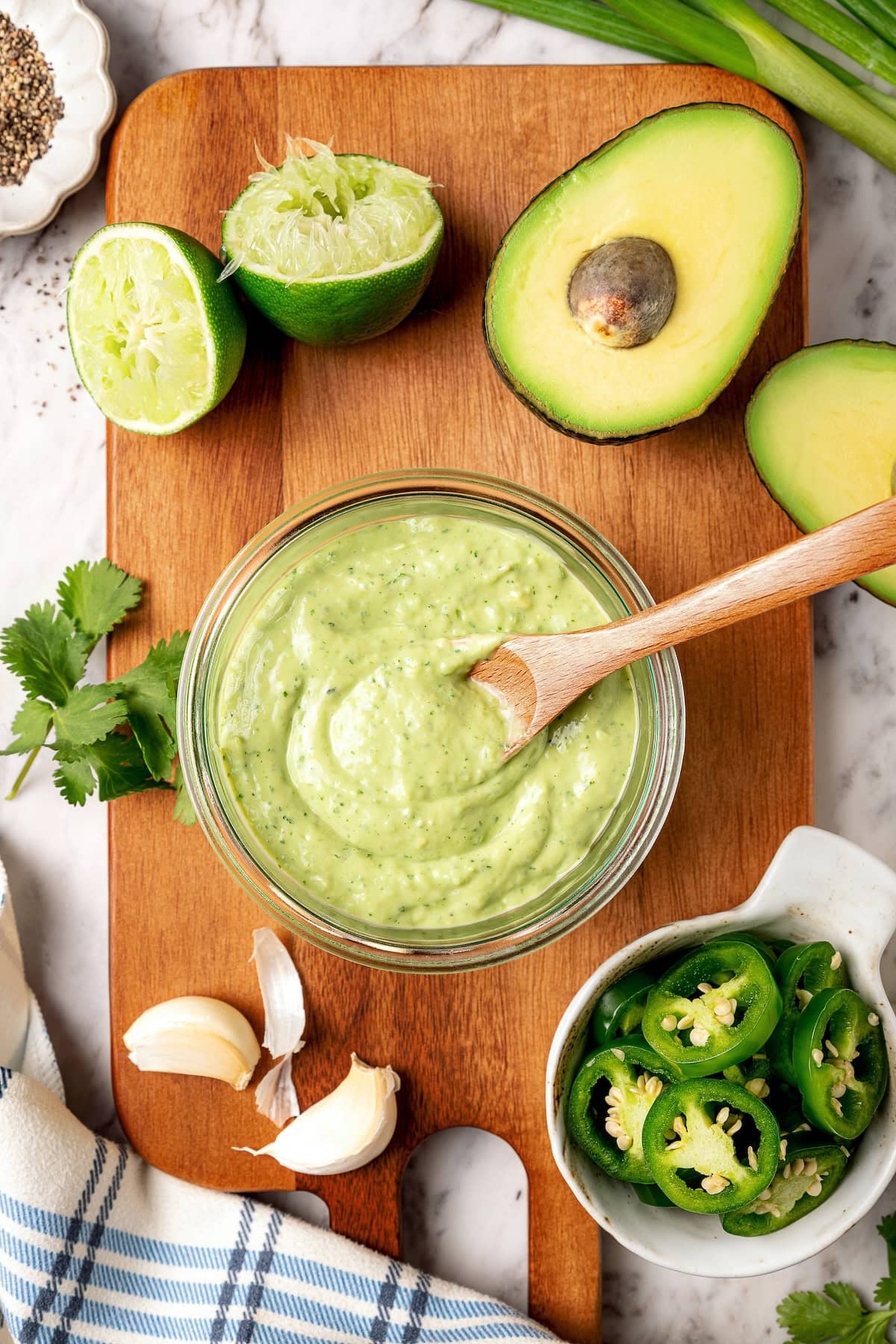Glass jar of avocado cilantro lime dressing with wooden spoon.