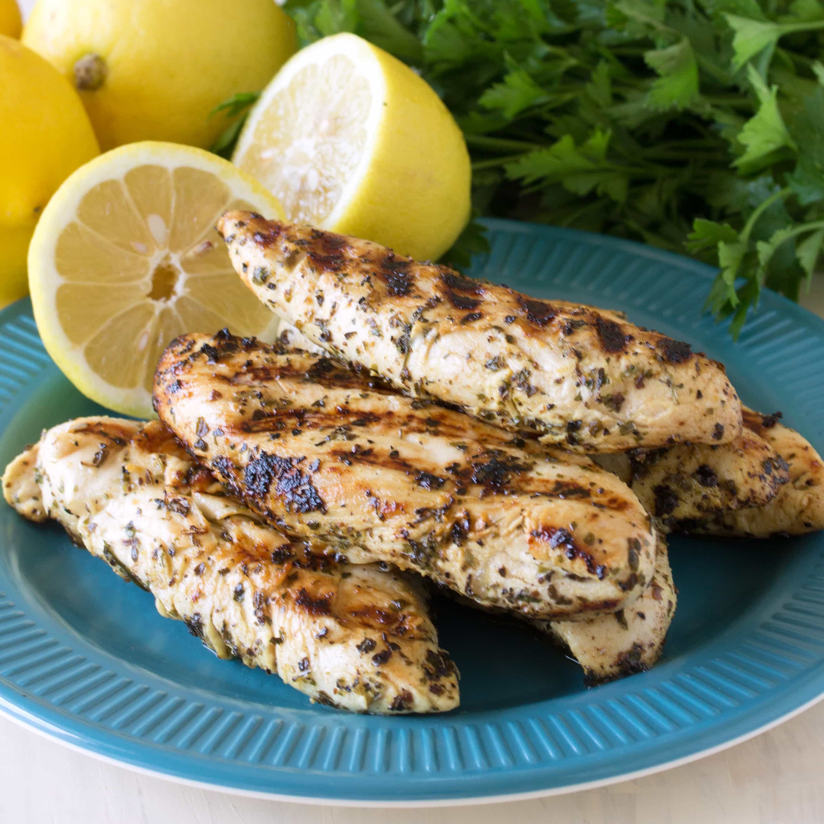 Grilled chicken tenders stacked on a blue plate.