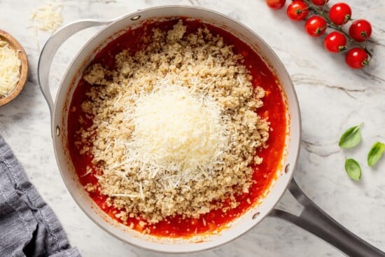 This healthy quinoa risotto swaps out the usual rice for protein-packed cooked quinoa. It's easy, creamy, and ready in just 15 minutes! Cheese and quinoa added to skillet of tomato sauce.