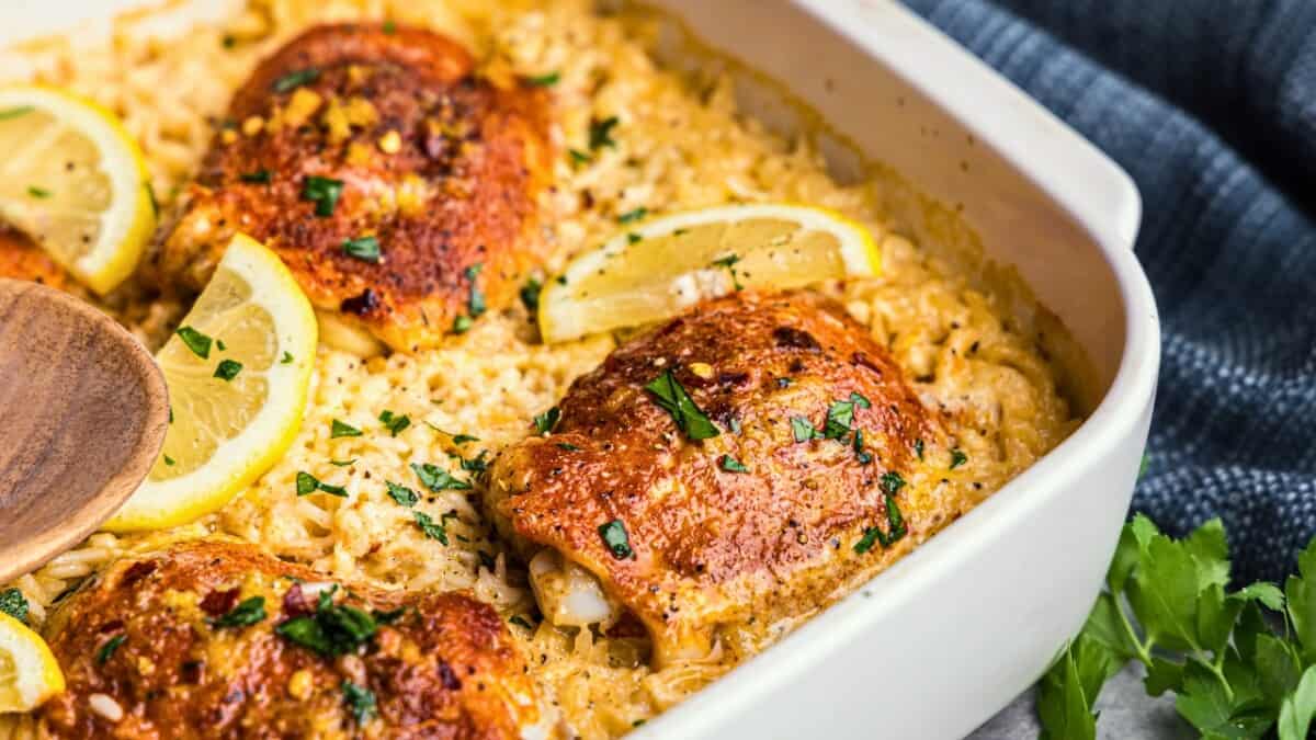 A close up view of a pan of fried chicken thighs with creamy garlic parmesan rice.