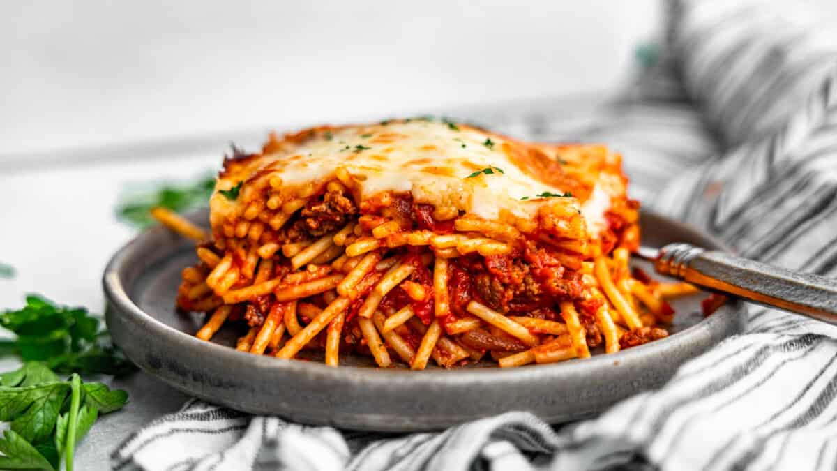 A helping of cheesy baked spaghetti on a plate.