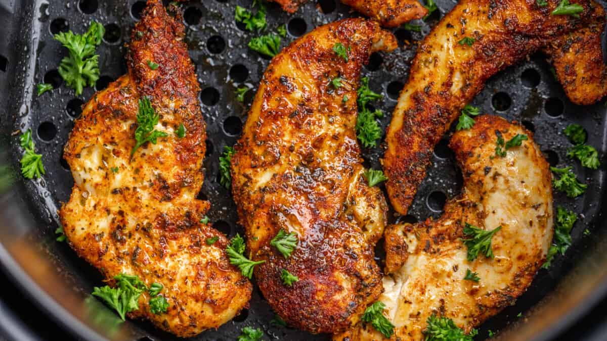 Close up view of naked chicken tenders in an air fryer.