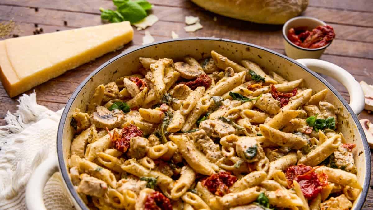 A cast iron pot full of One Pot Italian Chicken and Pasta with ingredients around.