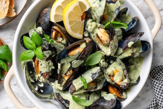 With tender mussels in cream sauce with Parmesan and basil, this recipe is perfect for special occasions, but easy enough for a weeknight! Bowl of mussels with basil cream sauce.