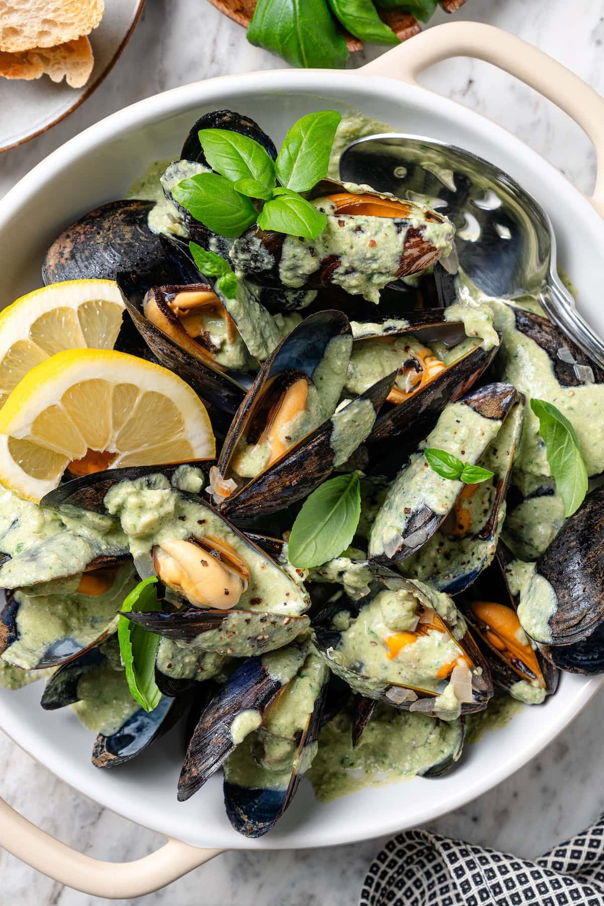With tender mussels in cream sauce with Parmesan and basil, this recipe is perfect for special occasions, but easy enough for a weeknight! Bowl of mussels in cream sauce with fresh basil and lemon.