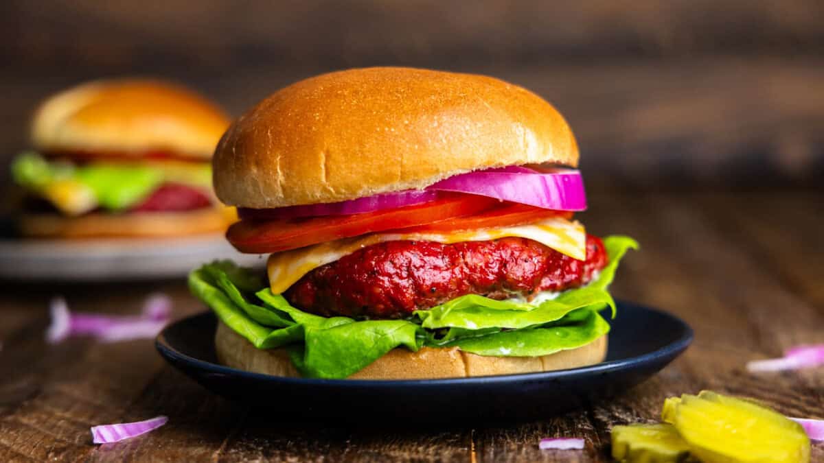 A close up view of a smoked burger on a black plate.
