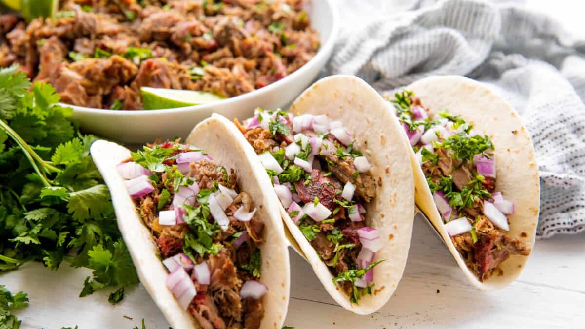 Smoked carnitas tacos in a taco holder.