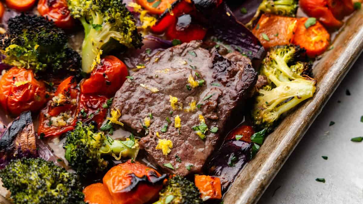 A close up overhead view of a sheet pan of Italian steak and veggies.