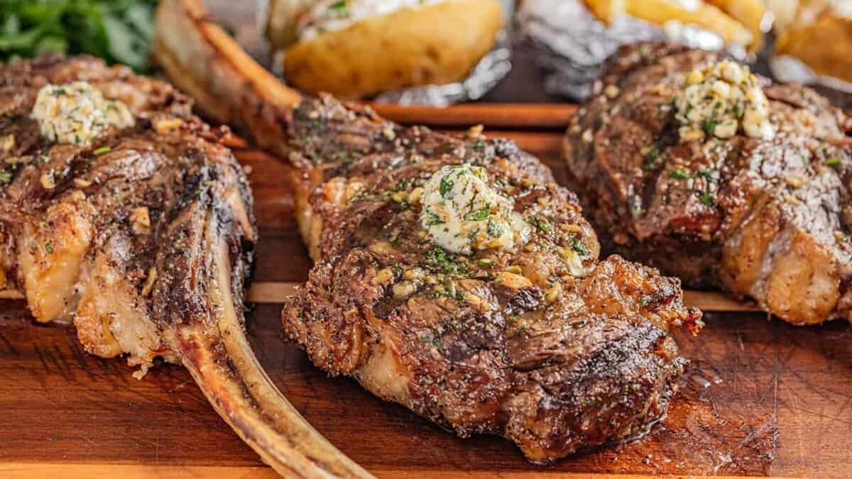 3 tomahawk steaks with compound butter on top.