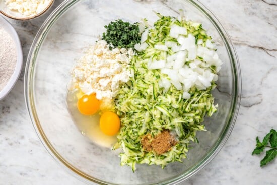 Ingredients for zucchini fritters in bowl before mixing.