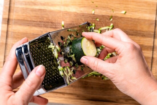 Grating zucchini on box grater.