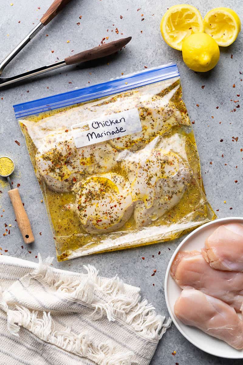 Sealed freezer bag filled with raw chicken breasts and homemade lemon pepper chicken marinade, ready to refrigerate or freeze for an easy meal prep recipe