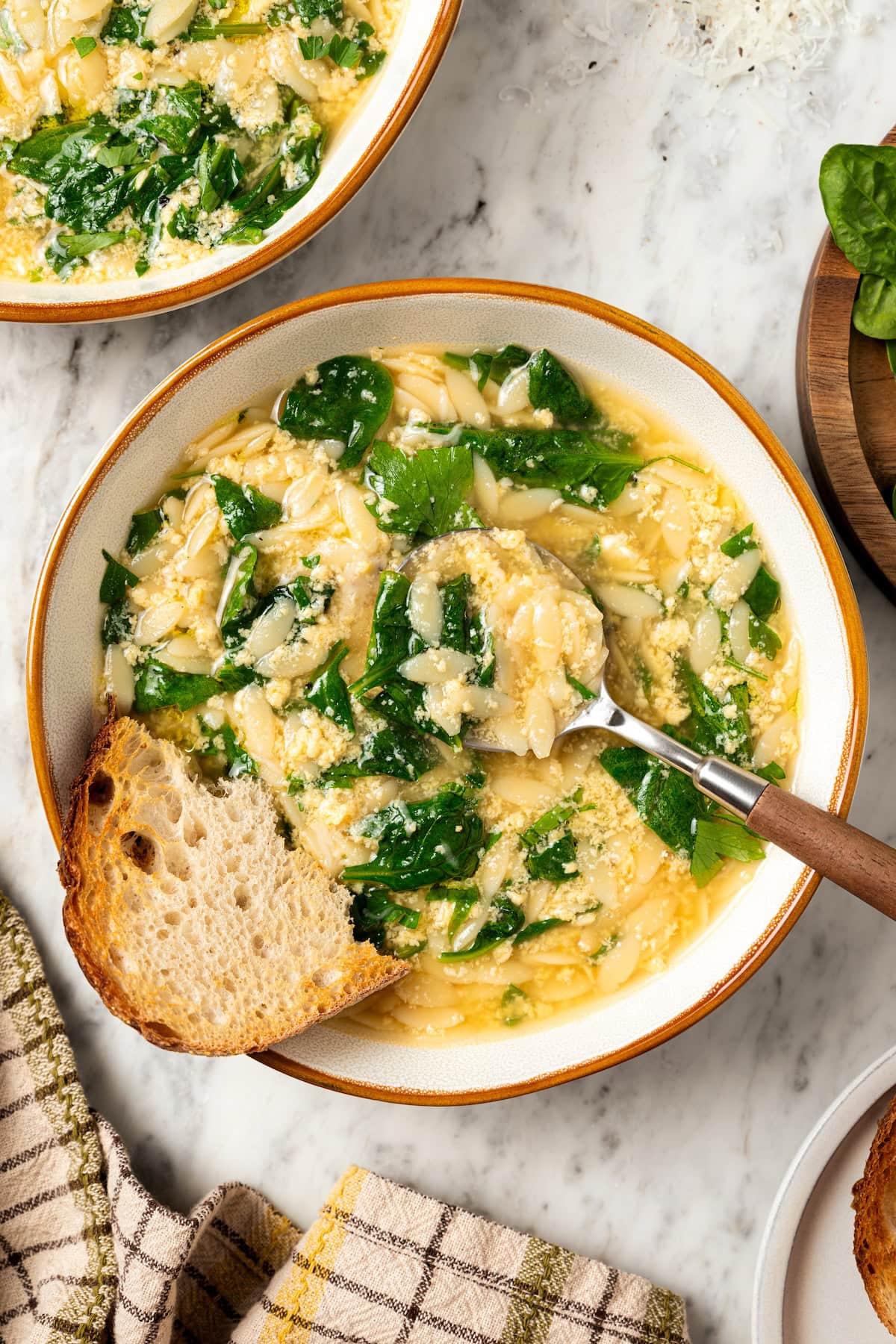 This cozy stracciatella soup is made with rich chicken broth, Parmesan, orzo and spinach for a satisfying meal. Done in just 20 minutes! Spoon in bowl of stracciatella soup with orzo and spinach.