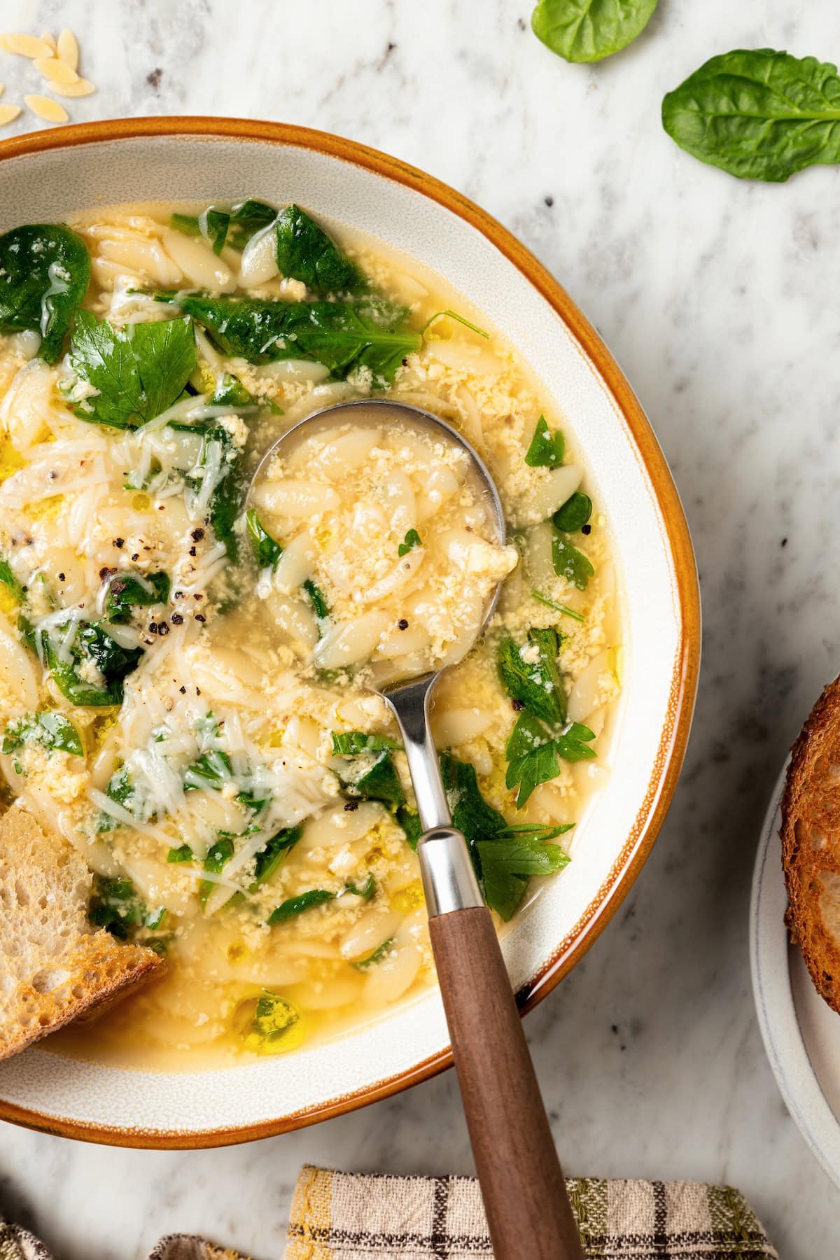 This cozy stracciatella soup is made with rich chicken broth, Parmesan, orzo and spinach for a satisfying meal. Done in just 20 minutes! Spoonful of stracciatella soup in bowl.