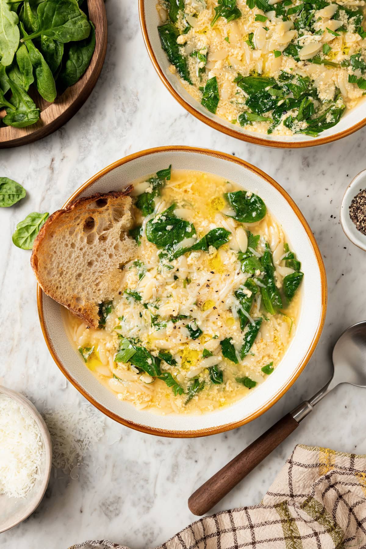This cozy stracciatella soup is made with rich chicken broth, Parmesan, orzo and spinach for a satisfying meal. Done in just 20 minutes! Two bowls of stracciatella soup with orzo and spinach.