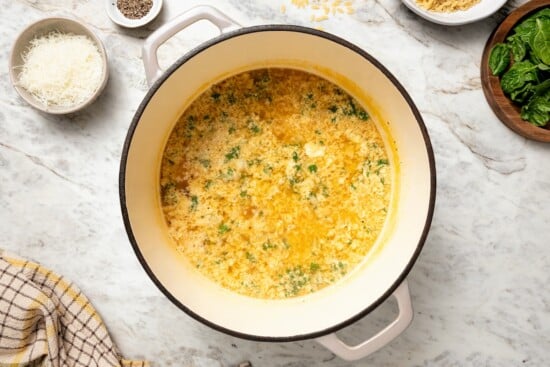 This cozy stracciatella soup is made with rich chicken broth, Parmesan, orzo and spinach for a satisfying meal. Done in just 20 minutes! Pot of stracciatella soup before adding spinach.