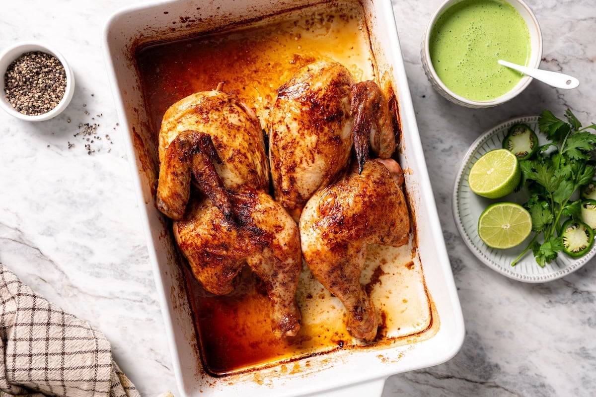 This juicy, restaurant-style Peruvian chicken is marinated overnight and oven-roasted for golden, crispy skin. Served with spicy green sauce. Golden, crispy roasted Peruvian chicken in a baking dish.