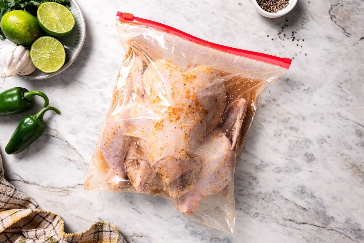 This juicy, restaurant-style Peruvian chicken is marinated overnight and oven-roasted for golden, crispy skin. Served with spicy green sauce. A whole chicken inside a Ziploc bag with Peruvian marinade.