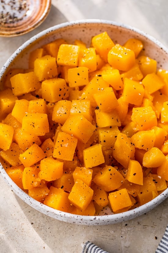 Diced maple roasted butternut squash with black pepper in a white bowl.