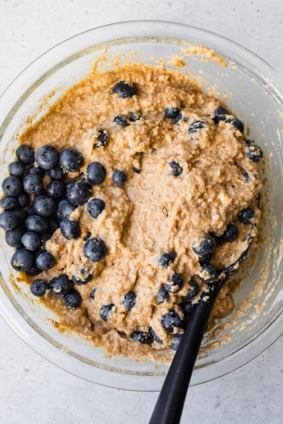 wet ingredients mixed in with blueberries in a bowl