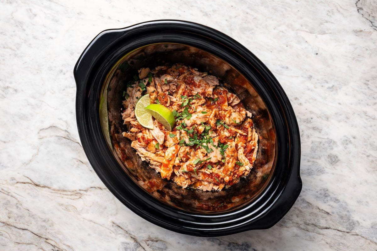 The easiest crockpot salsa chicken with juicy chicken thighs, jarred salsa, and simple spices. Great for meal prep, tacos, and rice bowls! Shredded salsa chicken inside the slow cooker.