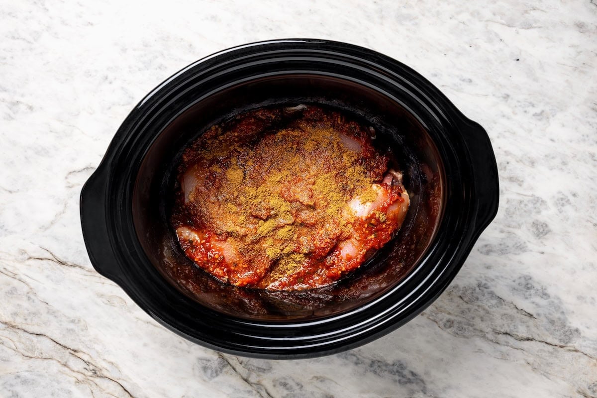 The easiest crockpot salsa chicken with juicy chicken thighs, jarred salsa, and simple spices. Great for meal prep, tacos, and rice bowls! Seasonings added to chicken and salsa inside the crockpot.