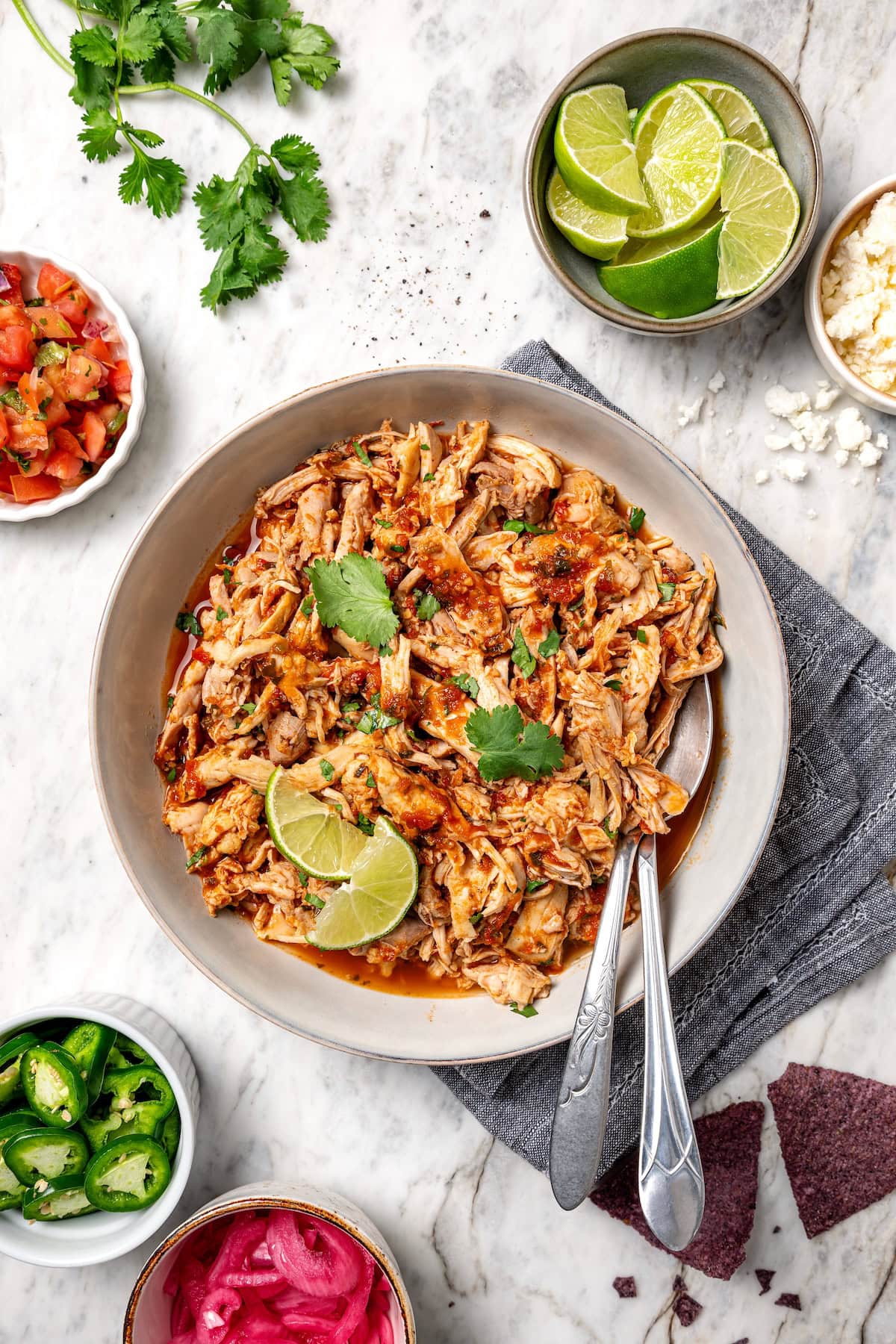 The easiest crockpot salsa chicken with juicy chicken thighs, jarred salsa, and simple spices. Great for meal prep, tacos, and rice bowls! Overhead view of crockpot salsa chicken served in a large bowl.