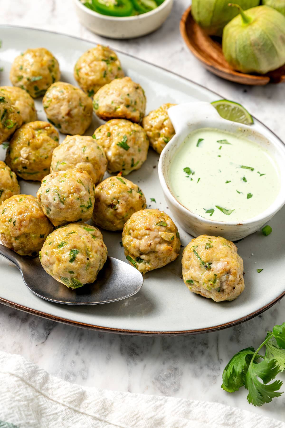 These Southwest baked turkey meatballs are made with jalapeño, cilantro and cumin for a light, tasty twist on classic meatballs! Add them to meal bowls and salads or serve them as an appetizer. Platter of baked southwest turkey meatballs with bowl of creamy dipping sauce.